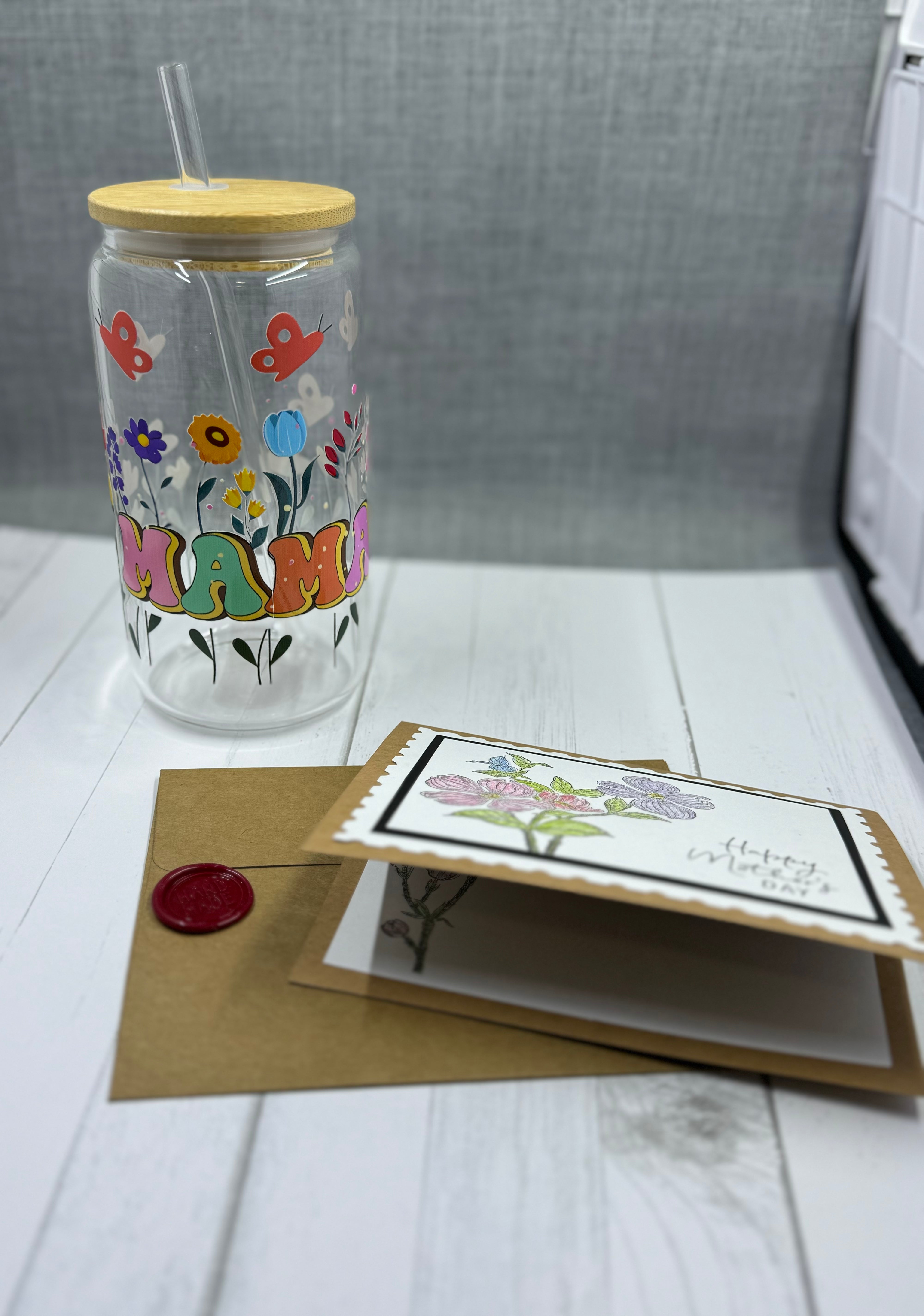 Celebrate Mother's Day with our MAMA Glass Tumbler Set. This 16oz tumbler features a unique UV DTF transfer, perfect for moms who appreciate quality and style. The set also includes a beautifully designed Mother's Day card with a wax seal for an extra personal touch. Show your love and appreciation with this thoughtful gift set.