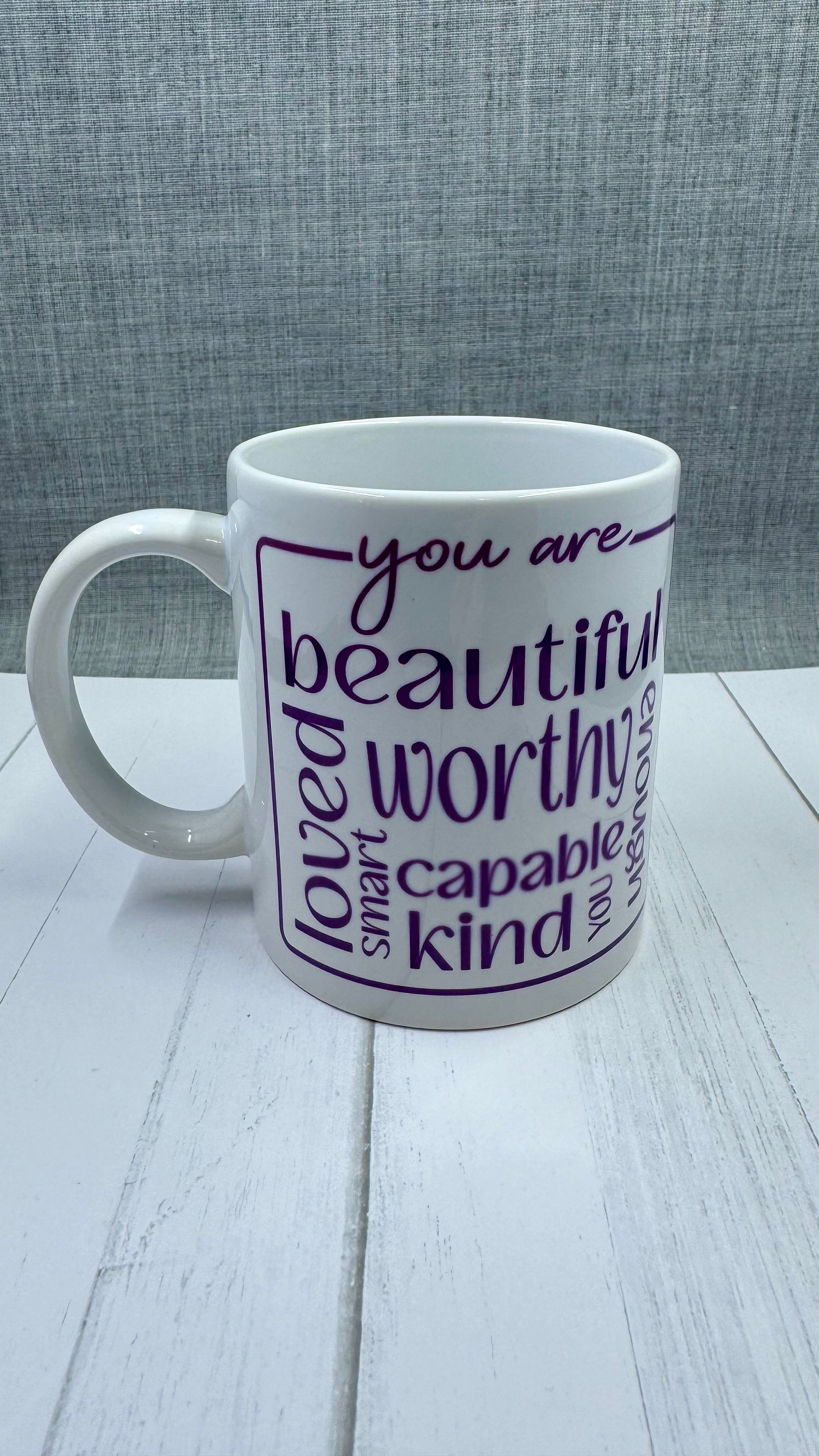 Our Affirmation Mug is a beautiful and durable ceramic mug that features an affirmation reminder that you are beautiful, loved, smart, capable, kind, worthy, and enough. The infusible ink used in the design process ensures long-lasting and vibrant colors, making this mug a perfect addition to any collection. Create a unique and stylish statement with this expertly crafted mug.