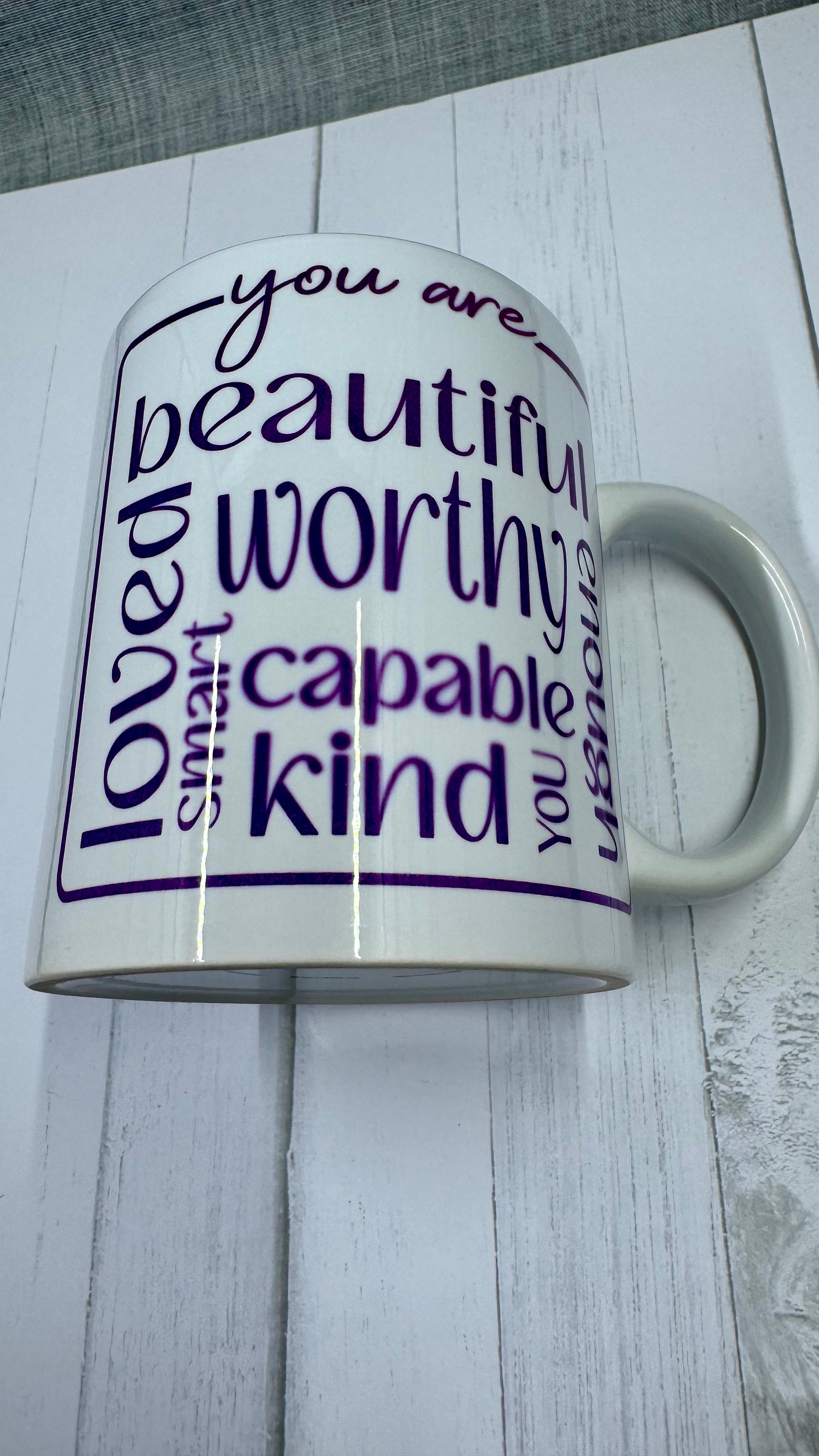 Our Affirmation Mug is a beautiful and durable ceramic mug that features an affirmation reminder that you are beautiful, loved, smart, capable, kind, worthy, and enough. The infusible ink used in the design process ensures long-lasting and vibrant colors, making this mug a perfect addition to any collection. Create a unique and stylish statement with this expertly crafted mug.